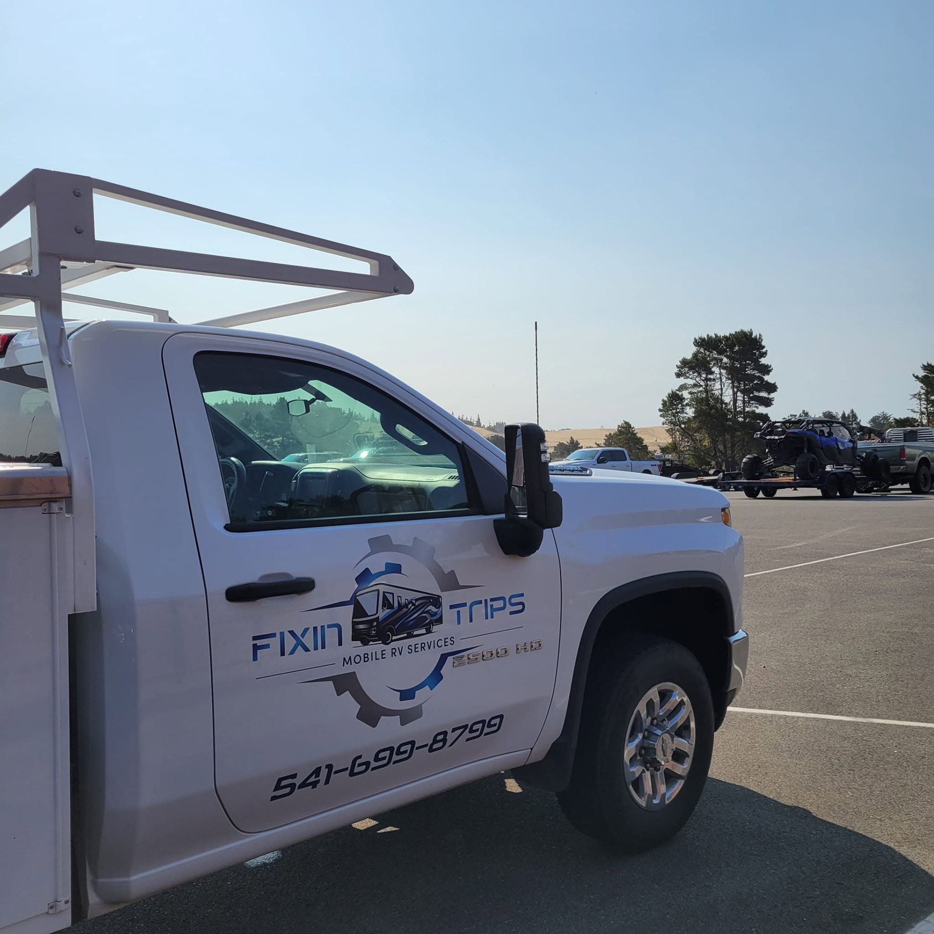 Fixin Trips branded white Chevrolet 2500 HD service truck with ladder rack, parked in Central Oregon